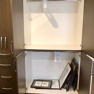 Immagine di un armadio o armadio a muro unisex moderno di medie dimensioni con ante lisce, ante con finitura invecchiata, pavimento in legno massello medio e pavimento marrone