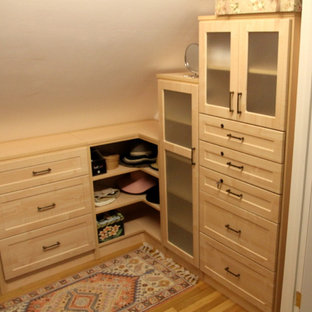 Ispirazione per una cabina armadio unisex stile americano di medie dimensioni con ante di vetro, ante in legno chiaro e parquet scuro