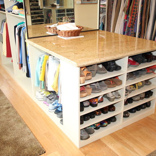 Immagine di un'ampia cabina armadio unisex con ante con bugna sagomata, ante beige e parquet chiaro
