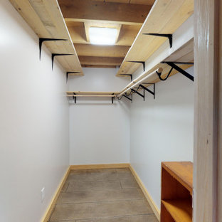 Lantlig inredning av ett mellanstort walk-in-closet för könsneutrala, med betonggolv och brunt golv