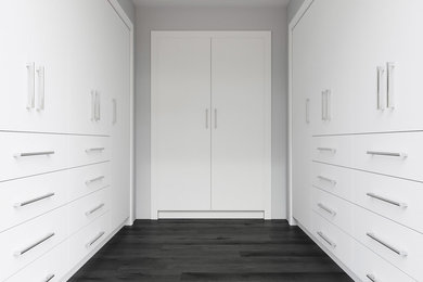 Imagen de armario vestidor moderno grande con armarios con paneles lisos, puertas de armario blancas, suelo de madera oscura y suelo negro