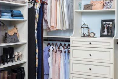 Ejemplo de armario vestidor unisex actual de tamaño medio con armarios abiertos, puertas de armario blancas y suelo de madera oscura