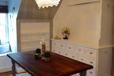 Diseño de armario vestidor unisex clásico de tamaño medio con armarios con paneles empotrados, puertas de armario blancas y suelo de madera en tonos medios