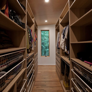 Diseño de armario vestidor unisex, retro, grande, con armarios abiertos, puertas de armario de madera clara, suelo de madera clara y suelo marrón