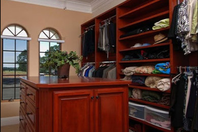 Diseño de armario vestidor unisex clásico grande con armarios con paneles con relieve, puertas de armario de madera en tonos medios, moqueta y suelo beige