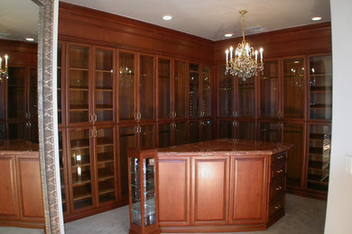 Ejemplo de armario vestidor unisex tradicional grande con armarios tipo vitrina, puertas de armario de madera en tonos medios y moqueta