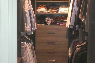 Foto de armario vestidor de hombre actual de tamaño medio con armarios con paneles lisos, puertas de armario de madera en tonos medios, suelo de madera clara y suelo marrón