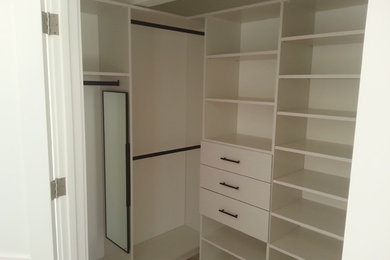 Example of a small trendy gender-neutral walk-in closet design in San Francisco with flat-panel cabinets and white cabinets