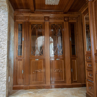Ejemplo de armario vestidor unisex, clásico, grande, con puertas de armario de madera oscura y suelo de travertino