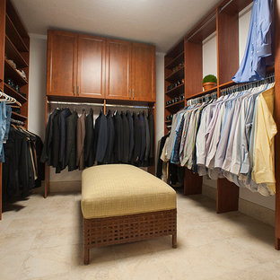 Diseño de armario vestidor de hombre, tradicional renovado, con armarios con paneles con relieve, puertas de armario de madera oscura, suelo de baldosas de porcelana y suelo beige