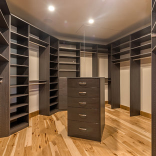 Idee per un'ampia cabina armadio unisex mediterranea con ante lisce, ante in legno bruno e parquet chiaro