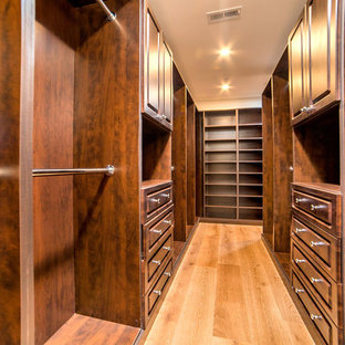 Modelo de armario y vestidor unisex, tradicional, con armarios con paneles con relieve, puertas de armario de madera en tonos medios, suelo de madera clara y suelo beige