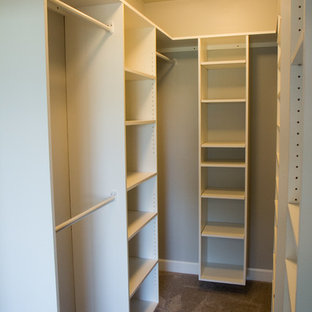 Example of a small classic gender-neutral carpeted walk-in closet design in Other with white cabinets