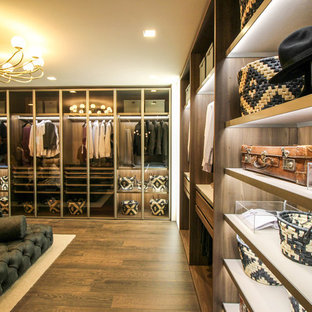 Ejemplo de vestidor moderno, extra grande, con armarios tipo vitrina, puertas de armario de madera oscura y suelo de madera en tonos medios