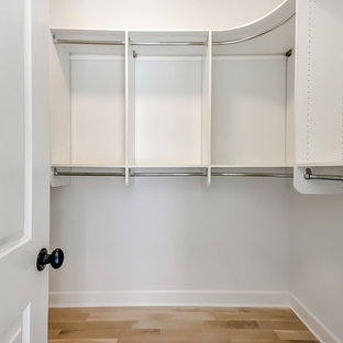Foto de armario vestidor unisex, campestre, grande, con armarios abiertos, puertas de armario blancas, suelo de madera clara y suelo beige