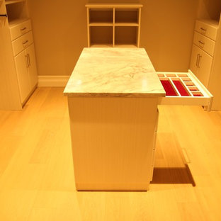 Immagine di un ampio spazio per vestirsi unisex mediterraneo con ante lisce, ante bianche e parquet chiaro