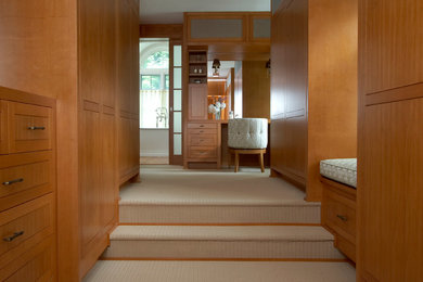 Modelo de vestidor unisex minimalista extra grande con armarios con paneles lisos, puertas de armario de madera clara, moqueta y suelo beige
