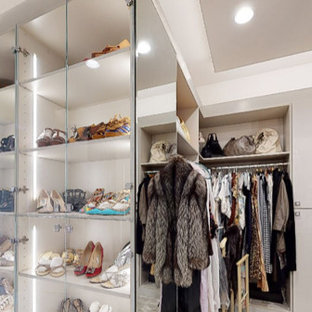 Ejemplo de armario y vestidor de mujer, moderno, grande, con armarios tipo vitrina, puertas de armario grises, moqueta y suelo gris
