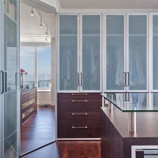 Inspiration för stora moderna walk-in-closets för könsneutrala, med luckor med glaspanel, bruna skåp och mörkt trägolv