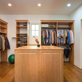 Immagine di una grande cabina armadio unisex mediterranea con ante con bugna sagomata, ante in legno chiaro e pavimento in legno massello medio