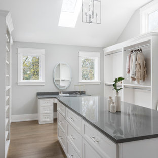 Imagen de vestidor de mujer y abovedado, de estilo de casa de campo, con armarios abiertos, puertas de armario blancas y suelo de madera en tonos medios