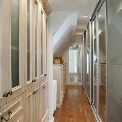 Large elegant gender-neutral medium tone wood floor dressing room photo in New York with recessed-panel cabinets and light wood cabinets