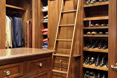 Ejemplo de vestidor de hombre clásico grande con armarios con rebordes decorativos, puertas de armario de madera oscura y suelo de madera en tonos medios
