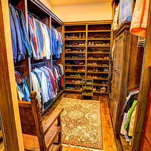 Foto di una grande cabina armadio unisex rustica con ante lisce, ante con finitura invecchiata e pavimento in legno massello medio