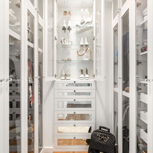 Immagine di una cabina armadio per donna tradizionale con ante in stile shaker, ante bianche, pavimento in legno massello medio e pavimento marrone