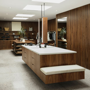 Esempio di grandi armadi e cabine armadio american style con ante lisce, ante in legno bruno, pavimento in cemento e pavimento grigio