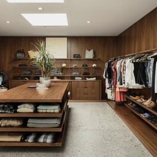 Idee per un grande spazio per vestirsi american style con ante in legno bruno, pavimento in cemento e pavimento grigio