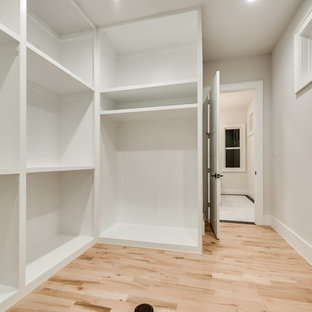 Immagine di una grande cabina armadio unisex contemporanea con nessun'anta, ante bianche, parquet chiaro e pavimento multicolore