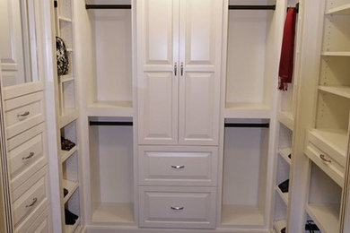 Diseño de armario vestidor unisex grande con armarios con paneles con relieve, puertas de armario blancas y suelo de madera oscura