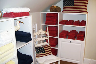 Imagen de armario vestidor unisex clásico de tamaño medio con armarios con paneles con relieve, puertas de armario blancas y suelo de madera en tonos medios
