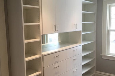 Large elegant gender-neutral walk-in closet photo in Other with flat-panel cabinets and white cabinets