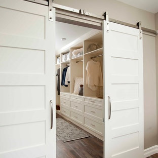 Diseño de armario vestidor unisex, clásico renovado, grande, con armarios abiertos, puertas de armario blancas, suelo de madera en tonos medios y suelo marrón