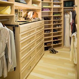 Immagine di una grande cabina armadio con ante con riquadro incassato, ante in legno chiaro e parquet chiaro
