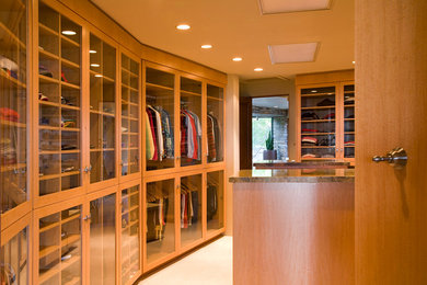 Large elegant gender-neutral beige floor walk-in closet photo in Phoenix with glass-front cabinets and medium tone wood cabinets