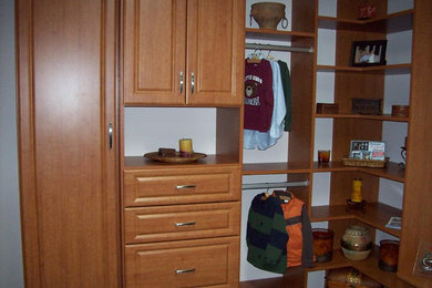 Example of a mid-sized minimalist gender-neutral walk-in closet design in Chicago with raised-panel cabinets and medium tone wood cabinets