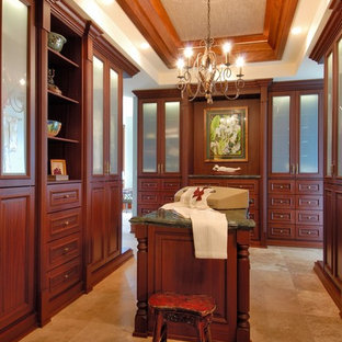 Diseño de vestidor clásico con puertas de armario de madera en tonos medios y suelo de travertino