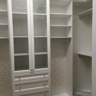 Immagine di una cabina armadio unisex stile marinaro con ante con riquadro incassato, ante bianche e parquet chiaro