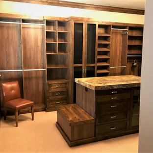 Esempio di una grande cabina armadio unisex classica con ante di vetro, ante in legno bruno, moquette e pavimento beige