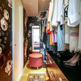 Ispirazione per una piccola cabina armadio per donna boho chic con ante lisce, ante nere, parquet chiaro e pavimento marrone