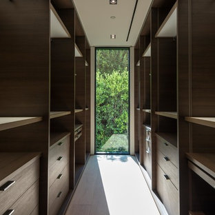 Immagine di una piccola cabina armadio unisex minimalista con nessun'anta, ante in legno bruno, parquet chiaro e pavimento beige