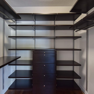 Immagine di una piccola cabina armadio unisex moderna con nessun'anta, ante in legno bruno, parquet scuro e pavimento marrone