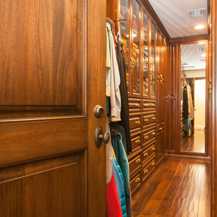 Esempio di una cabina armadio unisex mediterranea di medie dimensioni con ante con bugna sagomata, ante in legno scuro e pavimento in legno massello medio
