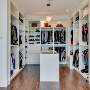 Modern inredning av ett mycket stort walk-in-closet för könsneutrala, med öppna hyllor, vita skåp, mellanmörkt trägolv och brunt golv