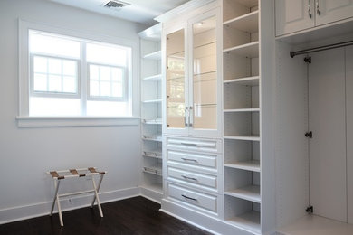 Imagen de vestidor unisex ecléctico de tamaño medio con puertas de armario blancas, suelo de madera oscura y armarios con paneles con relieve