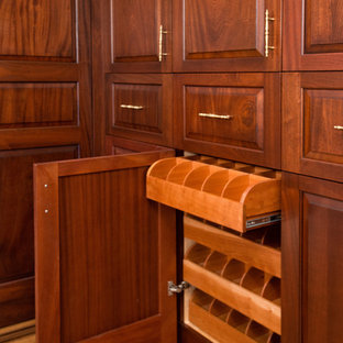 Idee per un ampio spazio per vestirsi unisex chic con ante con bugna sagomata, ante in legno bruno e pavimento in legno massello medio