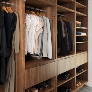 Idee per una grande cabina armadio unisex minimalista con ante lisce, ante in legno scuro e pavimento in cemento